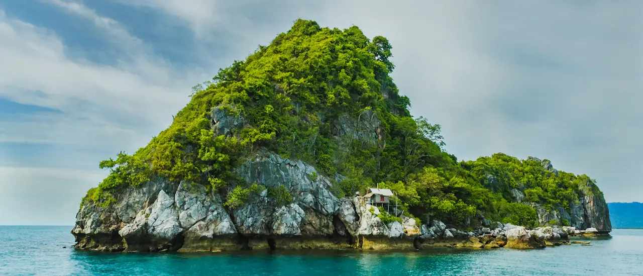 Isola rocciosa con vegetazione mediterranea e acqua turchese dell'arcipelago pontino