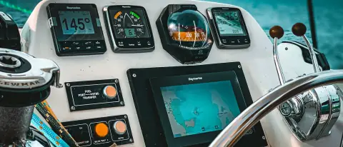 Plancia di comando di una barca a motore con timone, strumenti e manette