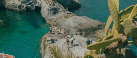 Cala con acqua turchese e barche all'ancora lungo la costa dell'isola di Ponza
