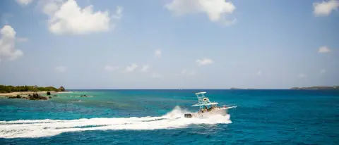 Motoscafo che naviga veloce su mare azzurro lungo la costa