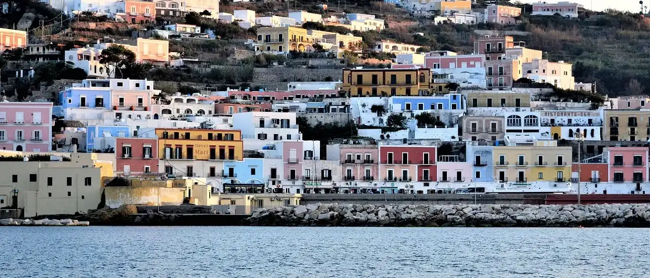 Il borgo di Ponza visto dal mare, con le case color pastello che salgono sulla collina sopra il lungomare