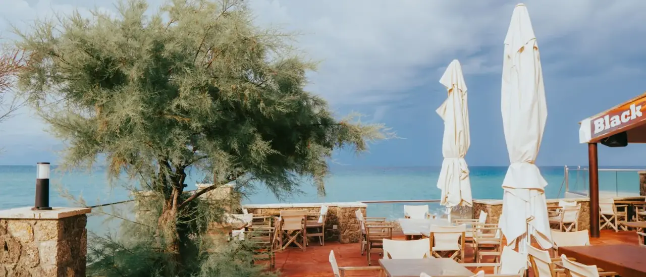 Terrazza di un ristorante con tavoli vuoti affacciati sul mare, pronta per il servizio