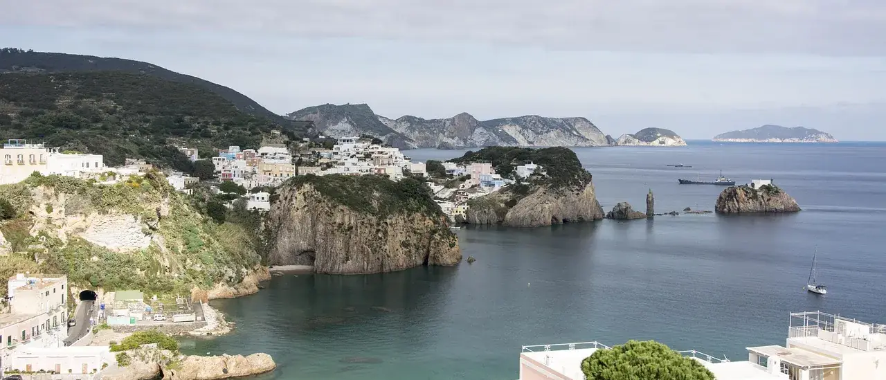 Veduta dall'alto della costa rocciosa di Ponza con il mare aperto e le altre isole pontine sullo sfondo