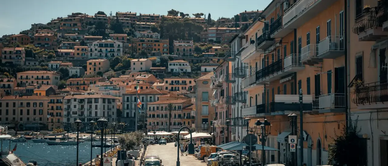 Il lungomare e le case colorate di Porto Santo Stefano, all'Argentario, con le barche ormeggiate nel porto