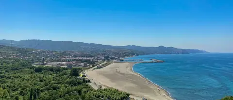 Litorale sabbioso con molo e mare turchese in una baia mediterranea