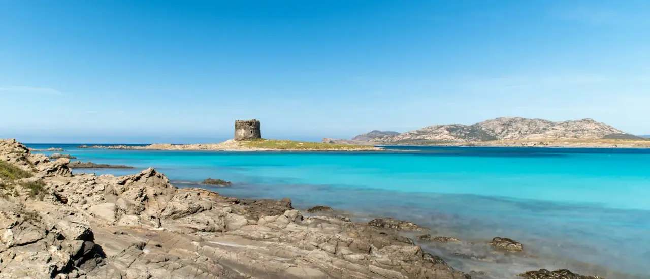 La spiaggia della Pelosa a Stintino con la torre aragonese e l'acqua turchese bassa