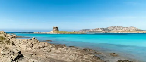 La spiaggia della Pelosa a Stintino con la torre aragonese e l'acqua turchese bassa