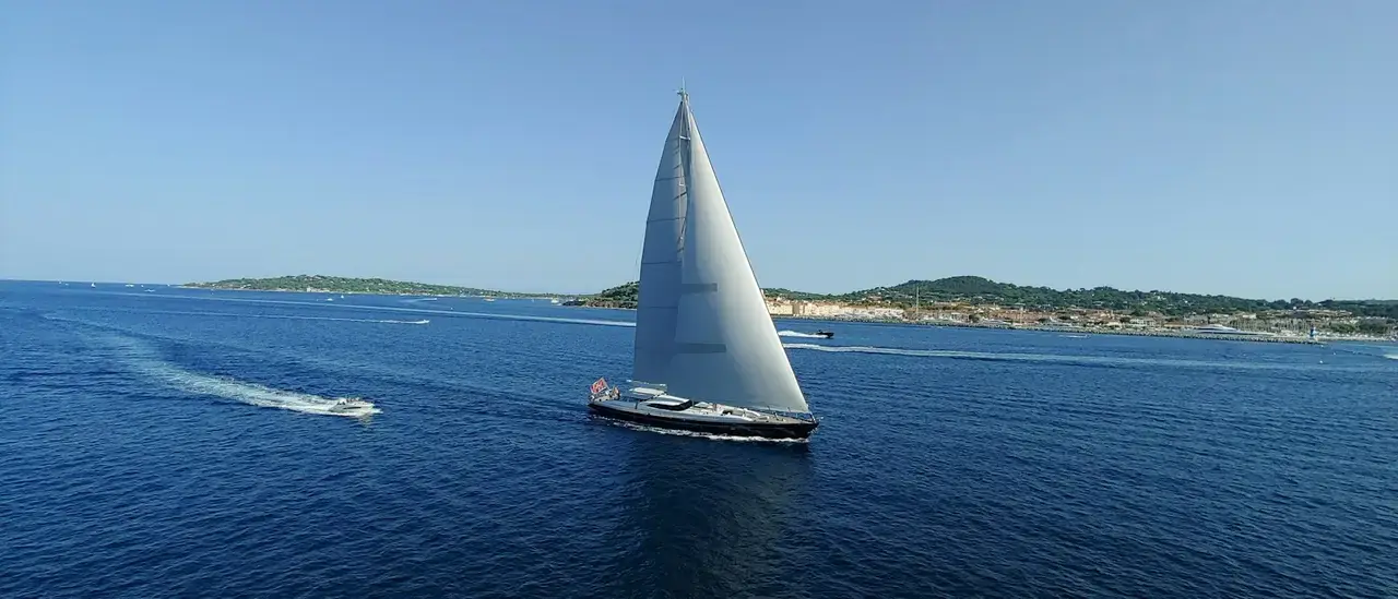 Barca a vela a vele spiegate lungo la costa in una giornata di sole